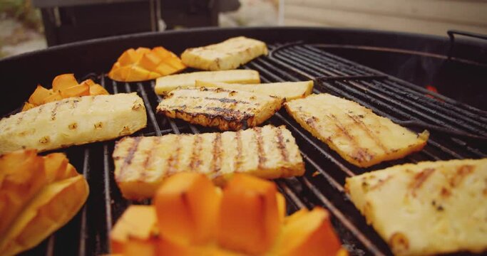 Fresh mango, pineapple slices and a wheel of brie cheese in a ramekin being placed on a barbecue grill