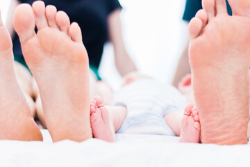 Obraz na płótnie Canvas White Baby feet from below compared with parents feets