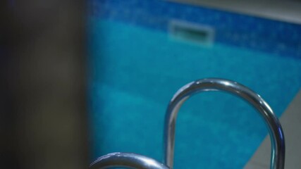 Gorgeous slim young tanned wet Caucasian woman with pierced navel walking out of swimming pool and leaving. Unrecognizable slender millennial walking away indoors. Beauty and femininity