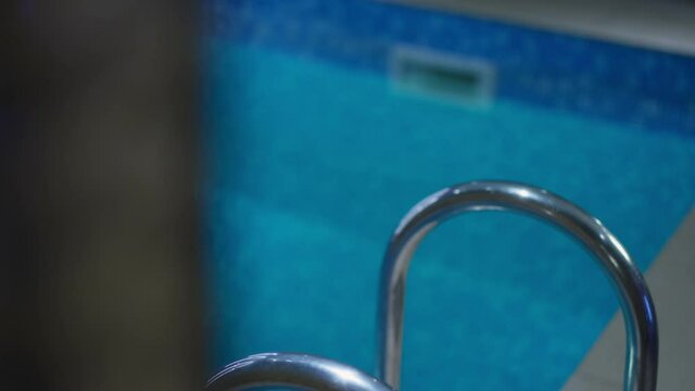 Gorgeous slim young tanned wet Caucasian woman with pierced navel walking out of swimming pool and leaving. Unrecognizable slender millennial walking away indoors. Beauty and femininity