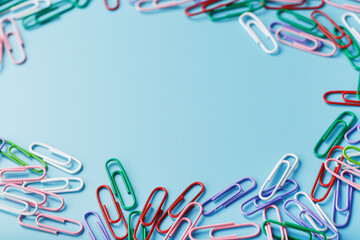 Colored paper clips on a blue background with free space
