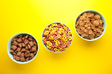 Variety of cereals in blue bowls, quick breakfast on yellow background.