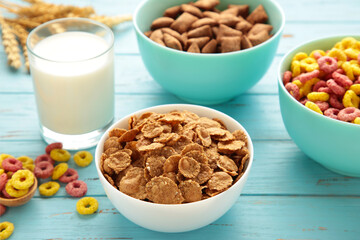 Variety of cereals in blue bowls, quick breakfast and milk on blue wooden background.
