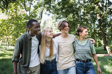 Smiling multiethnic teenagers looking away in park
