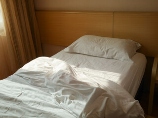 Unmade bed with crumpled duvet, bed sheet and pillow