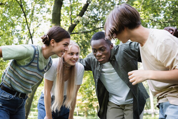 Smiling african american teenager hugging friends in park