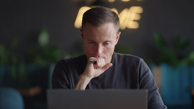 The man looks at his laptop and thinks. Decision-making in education and business. Thinking and inventing while sitting with a laptop