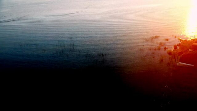 Flying over calm water on a relaxing golden sunset at golden house with land in sight surrounded by islands in idyllic location