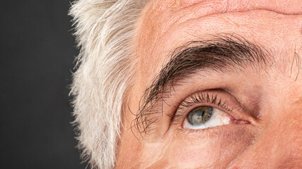 an elderly man's eye close up, wrinkles and crow's feet aging concept.