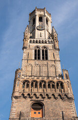 Brugge, Flanders, Belgium - August 4, 2021: Closeup of brown brick top half of Halletoren as part of Belfry against blue sky.