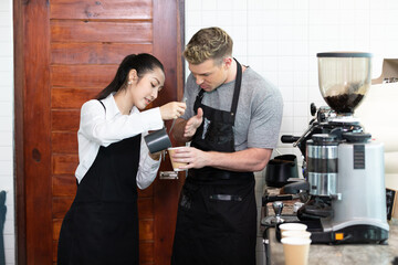 barista teaching trainee how to make a coffee from machine before opening in coffee shop