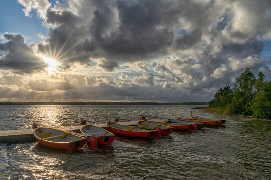 colorful rowbaots tied to a wooden floating dock in a beautiful lake landscape