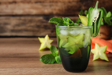 Spicy cocktail with jalapeno, carambola and mint on wooden table. Space for text