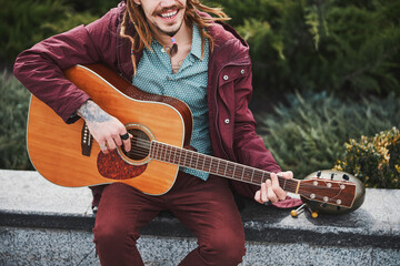 Happy musician playing the guitar on square