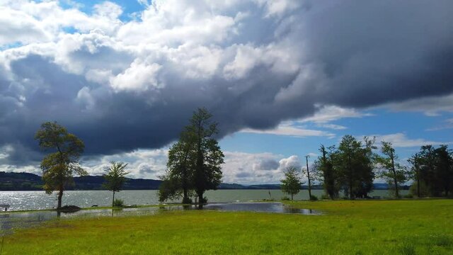 A panoramic view of the dramatic cloudscape over the peaceful lake and scenic landscapes, Sempach, Switzerland