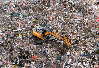 Garbage dump with construction waste. Excavator during recycling of waste at junk yard. Trash disposal and food waste. Dispose the rubbish in landfill. Trash disposal and rubbish dump with pollution.