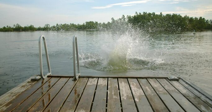 Adult male running jumping and cannonball splashing into the lake water