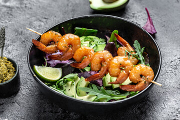 Vegetarian vegetable low carb lunch bowl with avocado, fresh salad, grilled shrimps and pesto sauce. Healthy diet seafood concept. Top view