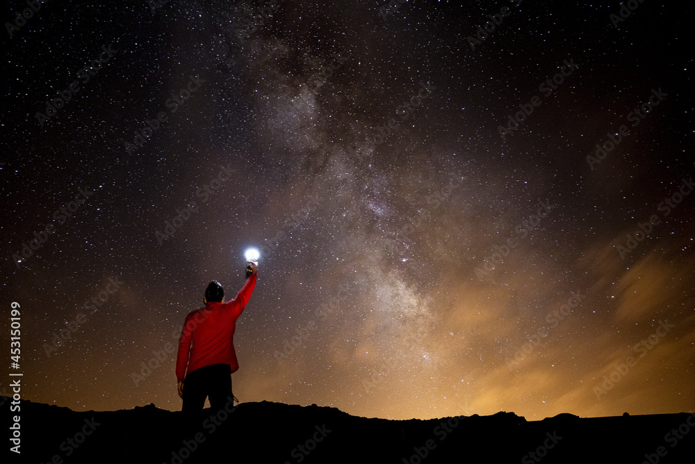 Poster male holding an illuminated flashlight under a galaxy starry sky