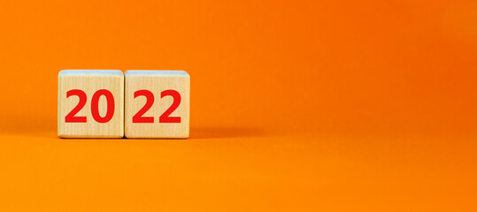 2022 happy new year symbol. Wooden cubes symbolize the change from 2021 to the new year 2022. Beautiful orange background. Copy space. Business and 2022 happy new year concept.