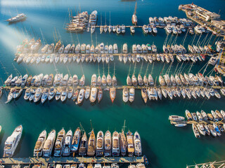 Aerial view of a lot of white boats and yachts moored in marina. Turkey Riviera during sunset, yachts in marina Aegean sea with sen rays. Luxury yacht moored in the bay © Aloshin Evgeniy