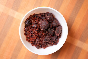 Some dry red rock salt crestal on a clay bowl on top of brown background