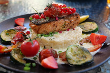 Delicious risotto with baked grilled salmon steak with berries and vegetables. Mediterranean cuisine, healthy food