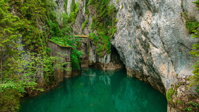 Photography shot from a drone at low altitude from above the water at Zanoaga gorges, located in Bucegi mountains, Romania. In the photo we can se the gorges and the dam with the wooden shacks.