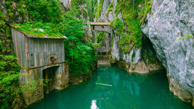 Photography shot from a drone at low altitude from above the water at Zanoaga gorges, located in Bucegi mountains, Romania. In the photo we can se the gorges and the dam with the wooden shacks.