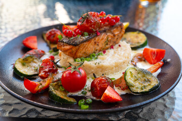 Delicious risotto with baked grilled salmon steak with berries and vegetables. Mediterranean cuisine, healthy food