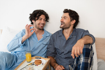 cheerful gay man eating blueberry near boyfriend