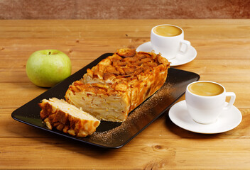 French apple cake. Homemade apple clafouti and two cups of coffee on wooden table. Shallow focus.