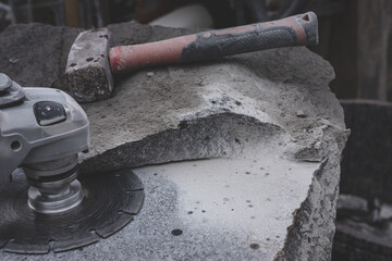 grinder worker cuts a granite stone the electric tool, hammer for hitting off stone chips, work in progress, granite workshop, monument building studio - obrazy, fototapety, plakaty