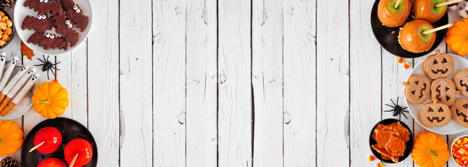 Rustic Halloween treat double border over a white wood banner background with copy space. Above view. Assorted candied apples, cookies, candy and sweets.