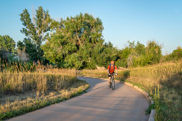 Senior male cyclist is commuting on a bike trail in Fort Collins in northern Colorado, late summer...