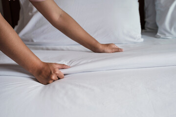 Hands of hotel maid making the bed in the luxury hotel room ready for tourist travel