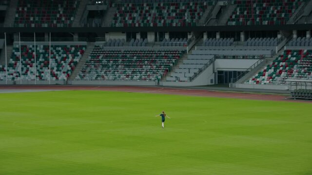 ZOOM OUT Caucasian pre teen girl entering the field of huge soccer stadium, holding a ball, dreaming of becoming professional player, soccer star