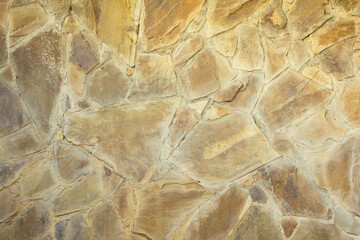 Wall clad with yellow-brown flat stones bonded with cement
