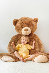 Sweet happy child boy playing with his giant teddy bear, indoor at home