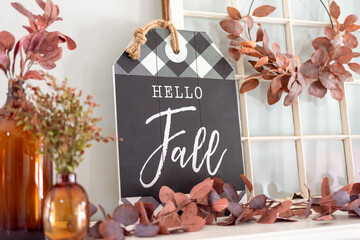 Closeup of Hello Fall sign and leaves on a mantel decorated for autumn