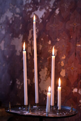 group of church candles lit over beautiful old painted wall