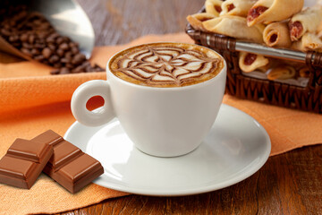 xícara de café expresso decorado com barra de chocolate no pires em fundo de mesa.