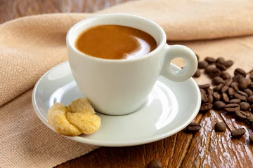 Fotobehang xícara de café em close com biscoito no pires em fundo de madeira. © Mauricio