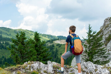 Naklejka na ściany i meble little boy with backpack hiking in mountains. Cute boy with hiking equipment in the mountains. Hiking in mountains on summer.