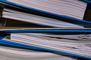 Closeup view of the documents in the blue binders piled on top of one another