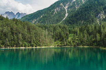 Fototapeta na wymiar A view to an emerald green Blindsee lake surrounded by forest