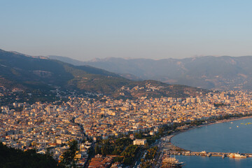 Alanya city (Turkey) harbor in the evening. Buildings. Bay with boats and ships. Mountains and sea.