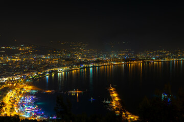 Fototapeta premium Kizil Kule tower in Alanya bay vith boats and ships, view from peninsula castle, Antalya district, Turkey. Famous tourism destination. Night cityscape.