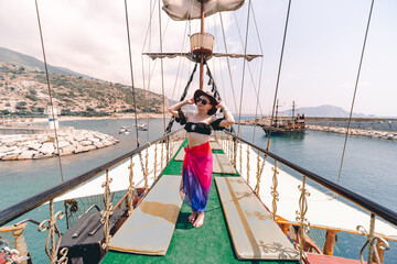 Happy girl posing at old pirate ship on the water of Mediteranean sea. Tourist entertainment,...
