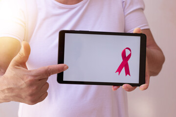 Mature woman holding tablet with a pink ribbon.